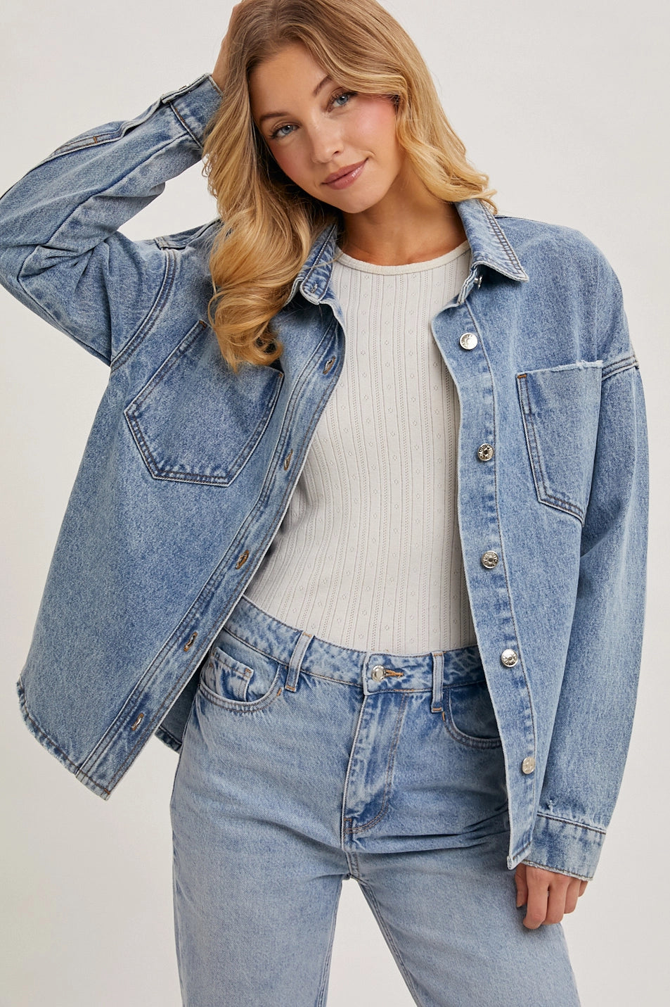 Woman wearing a denim jacket and jeans on a plain background