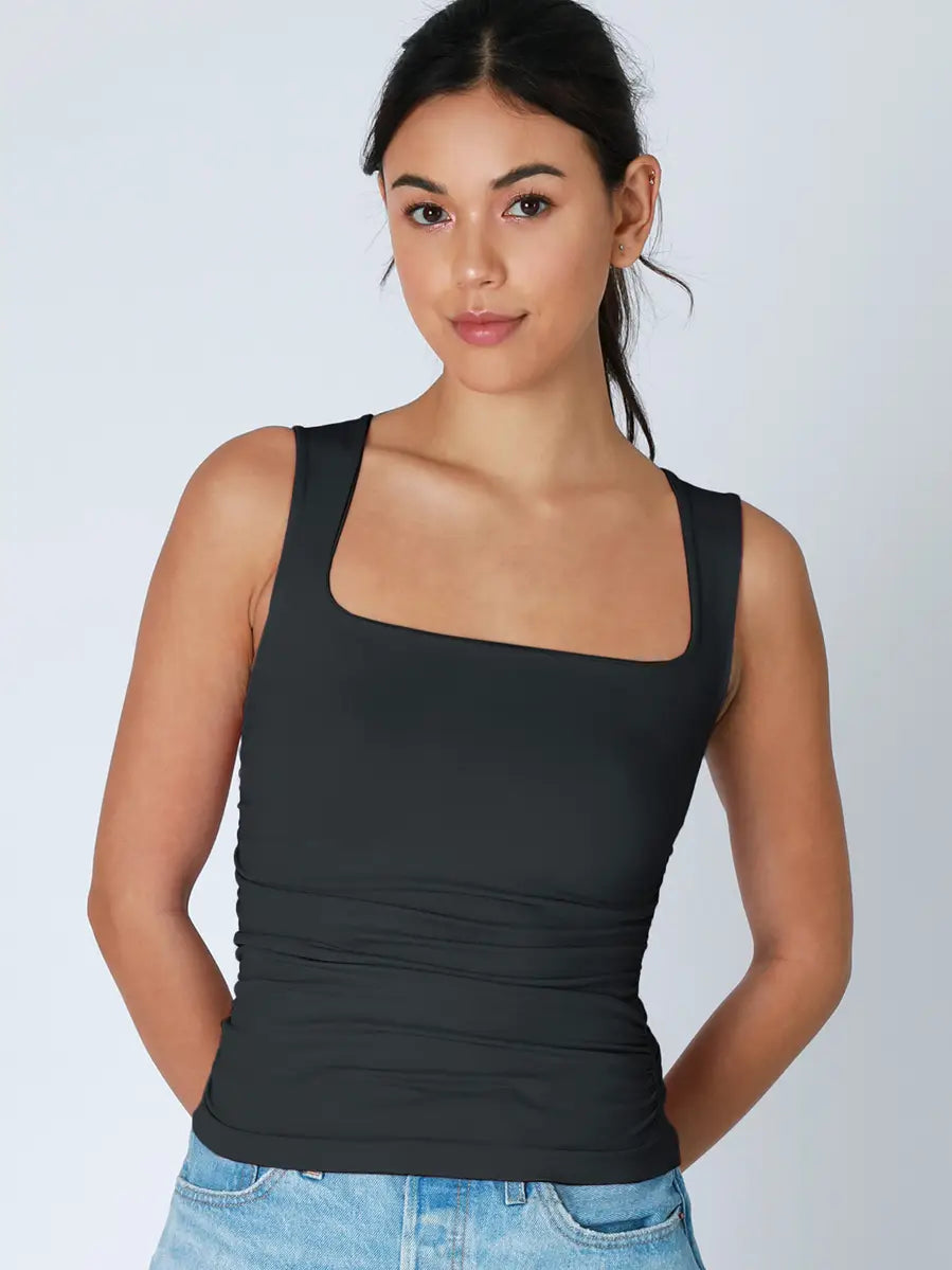 Woman wearing a black tank top against a plain background