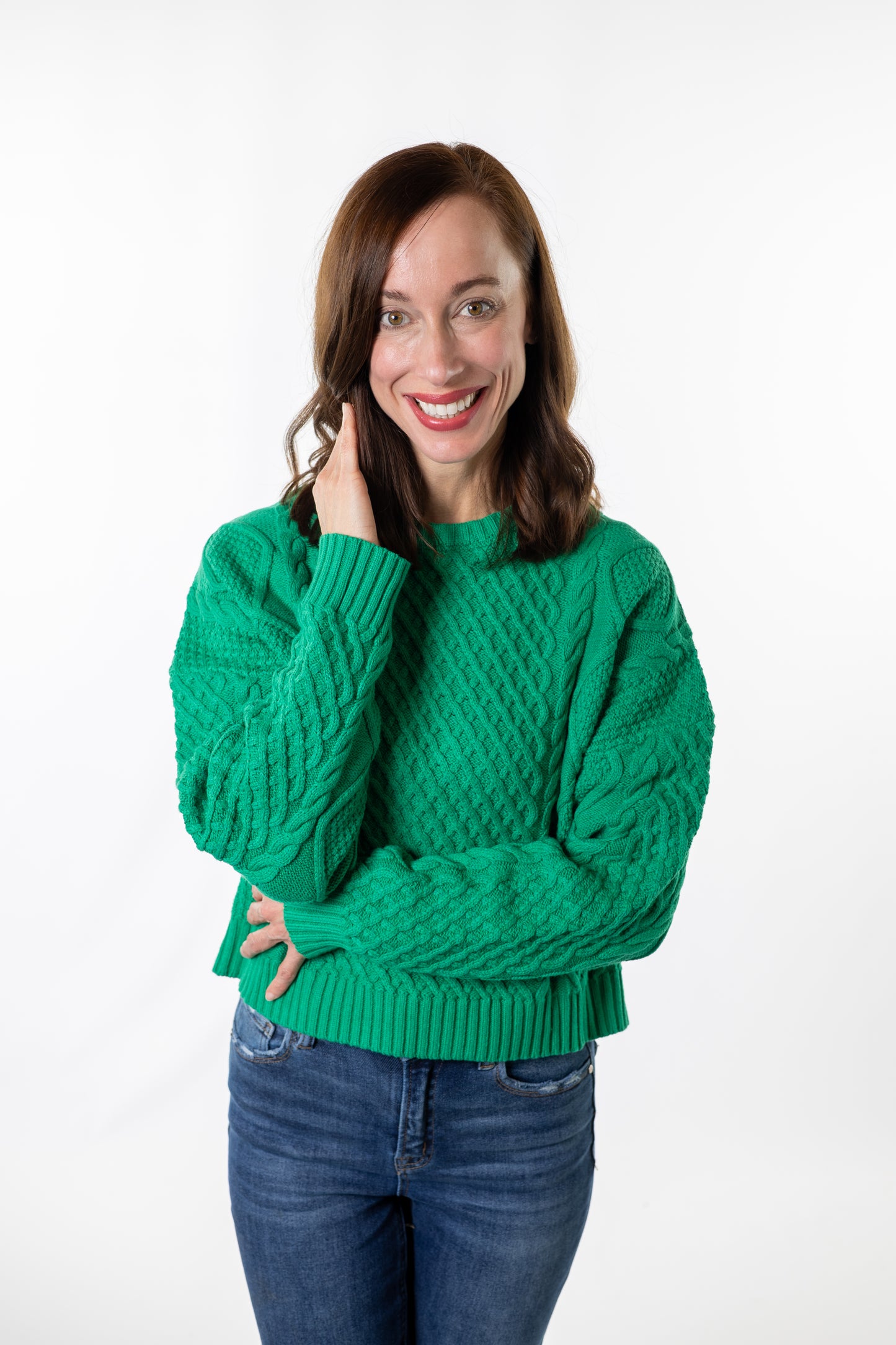 Woman wearing a emerald green sweater on a white background