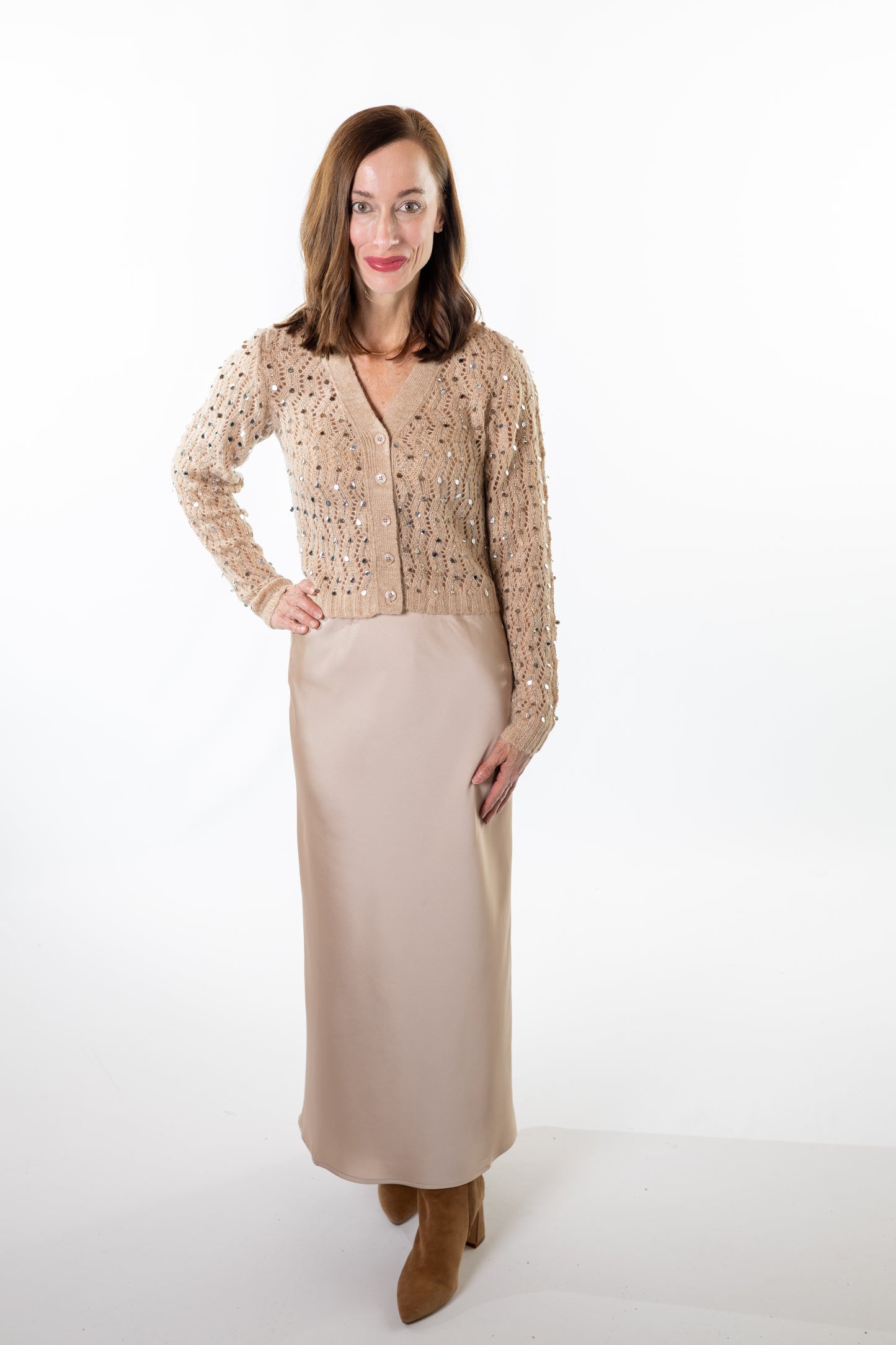 Woman wearing a beige sequin cardigan and champagne skirt