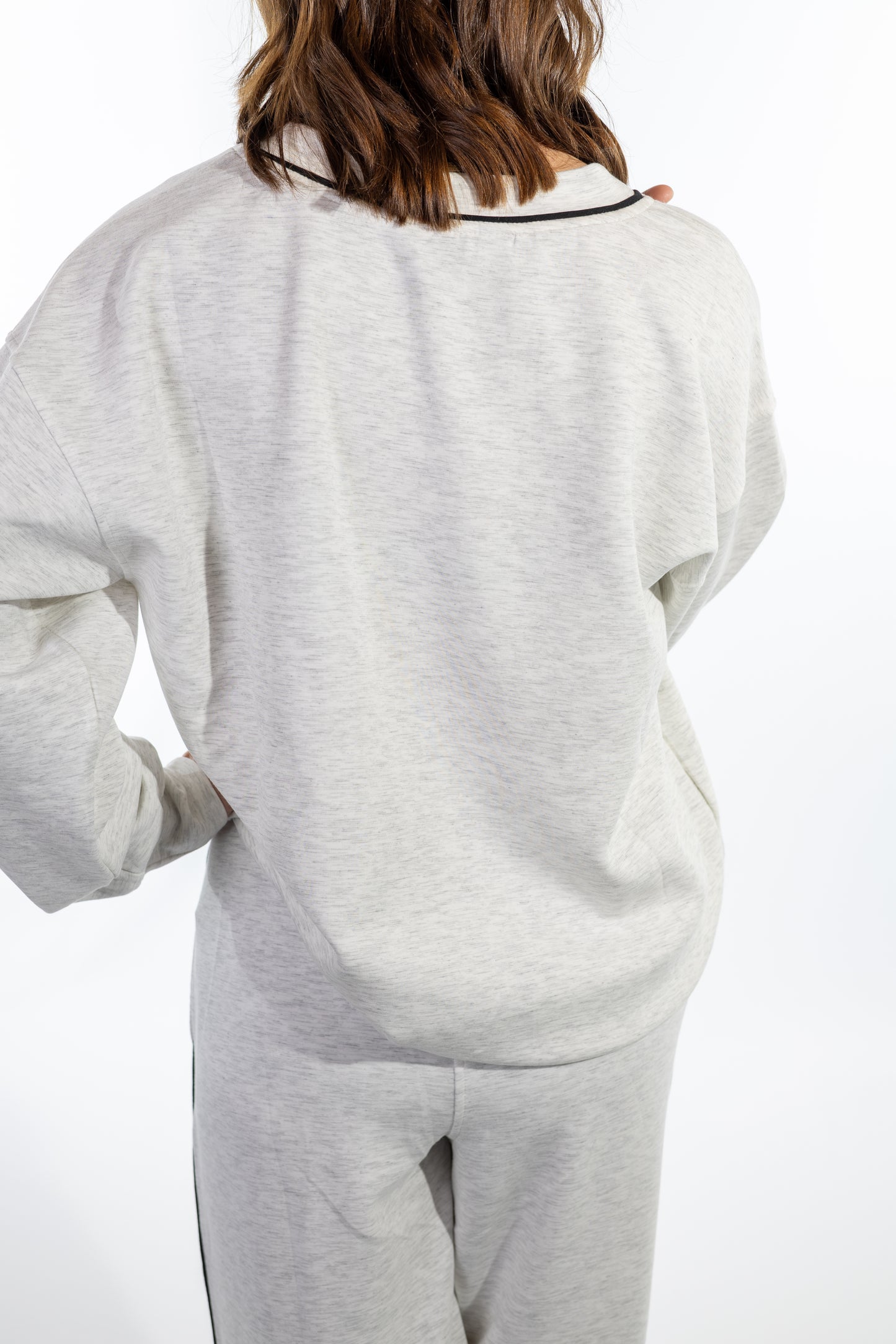 Person wearing a light gray scuba sweatshirt and pants on a white background