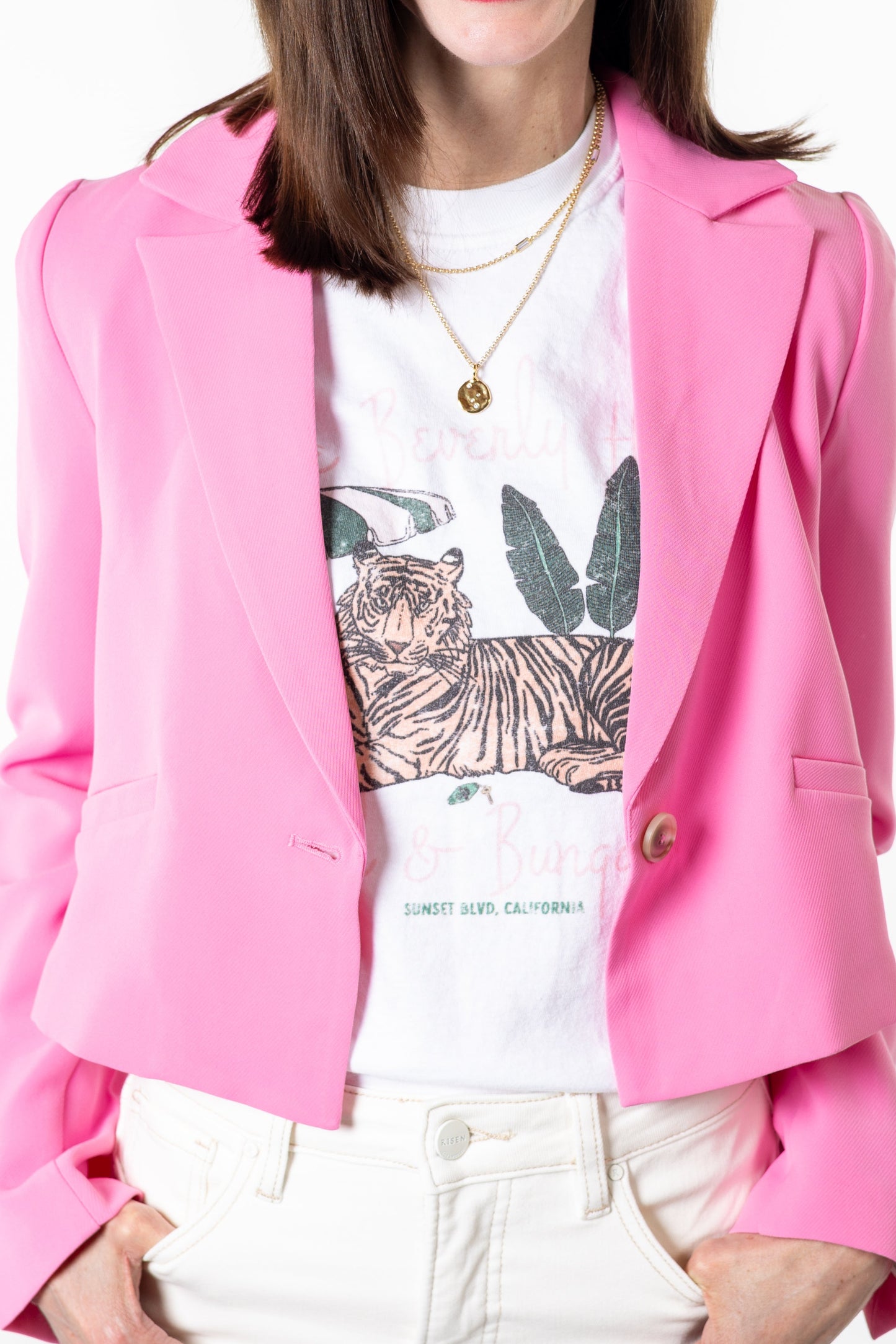 Woman wearing a pink blazer over a white shirt with a graphic design, on a white background