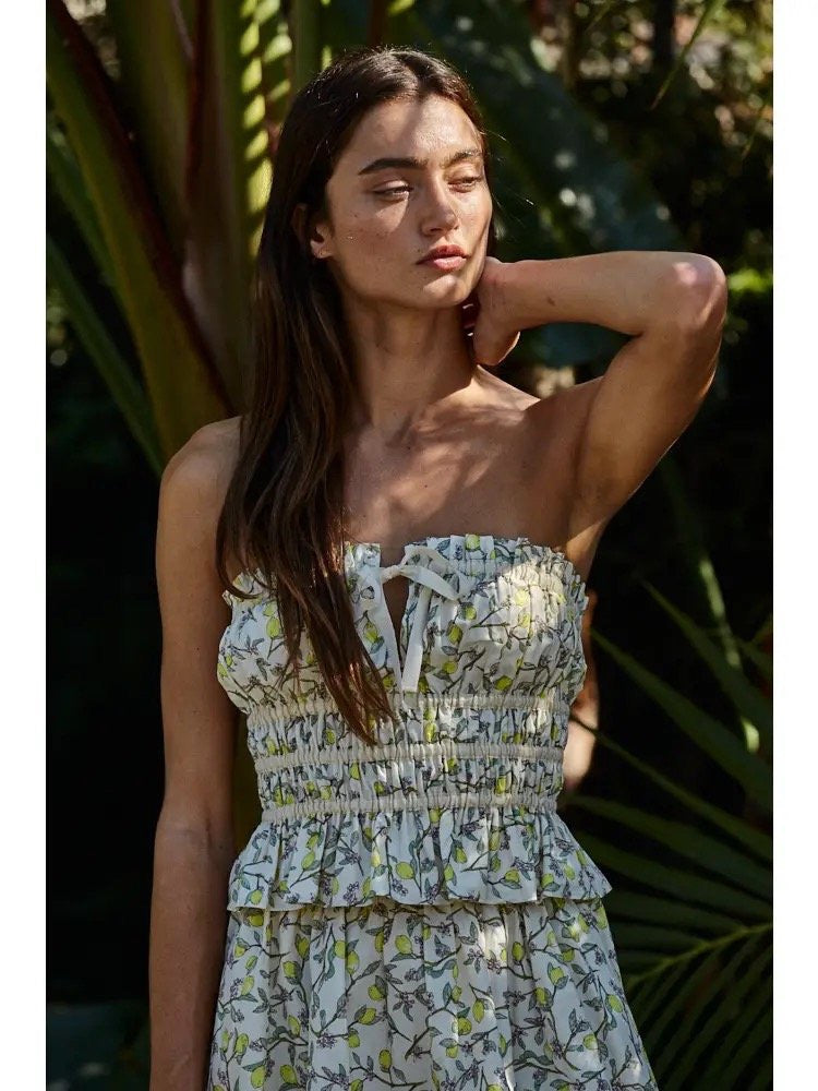 A woman wearing a strapless, smocked, floral print top with a tie at the front.