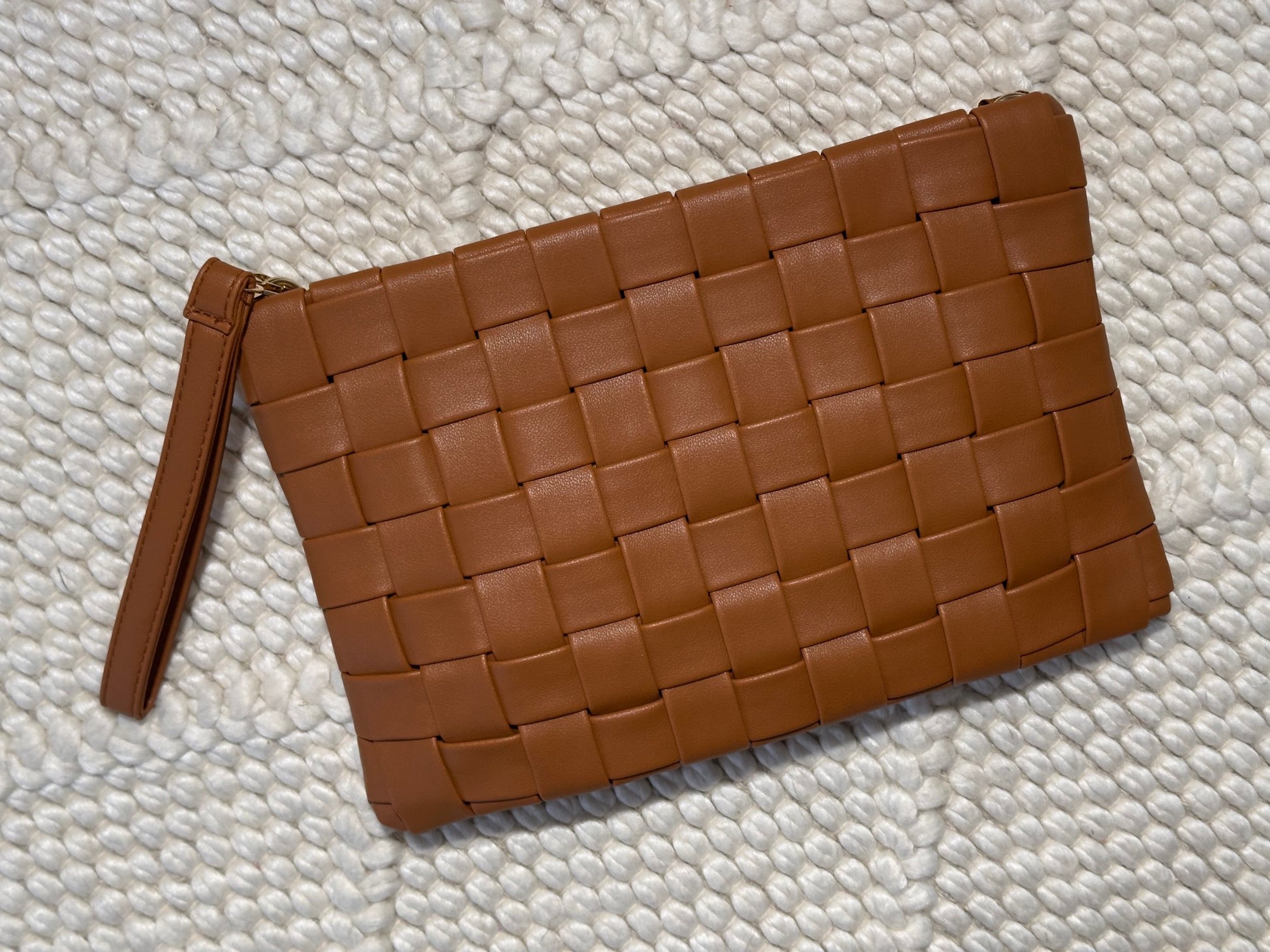Brown woven clutch bag on a textured white surface