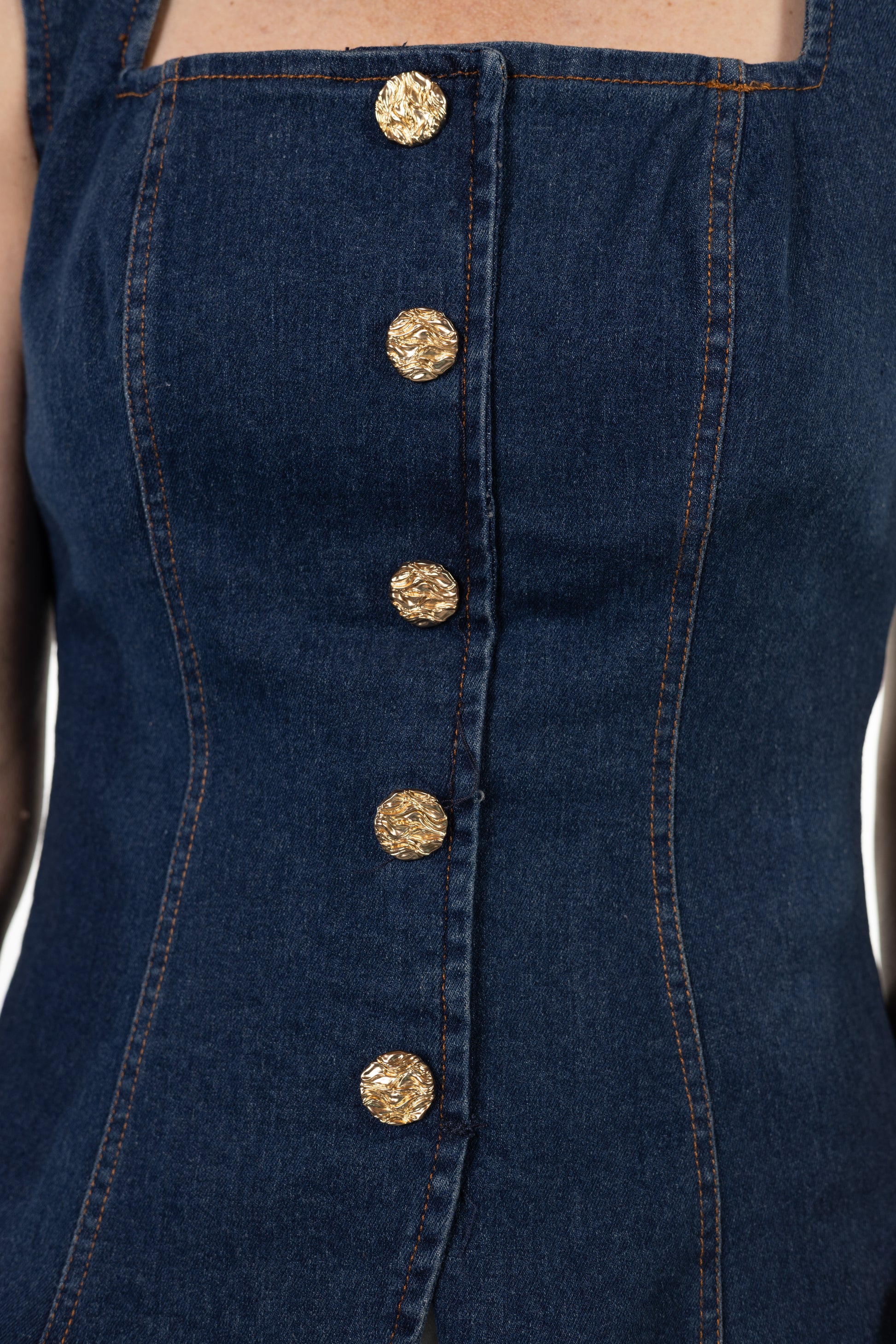 Close-up of a navy blue denim dress with gold buttons.