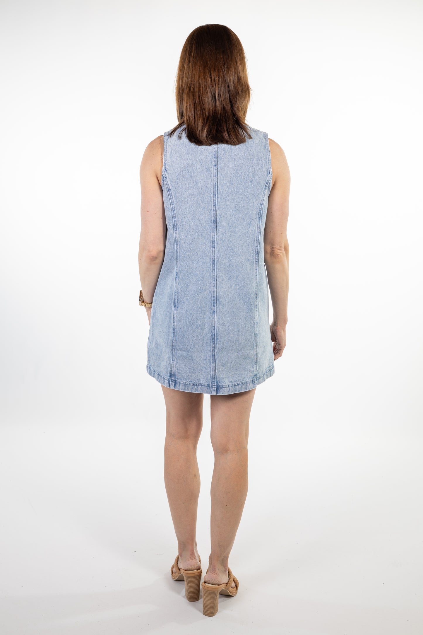 Woman wearing a light blue denim dress on a white background