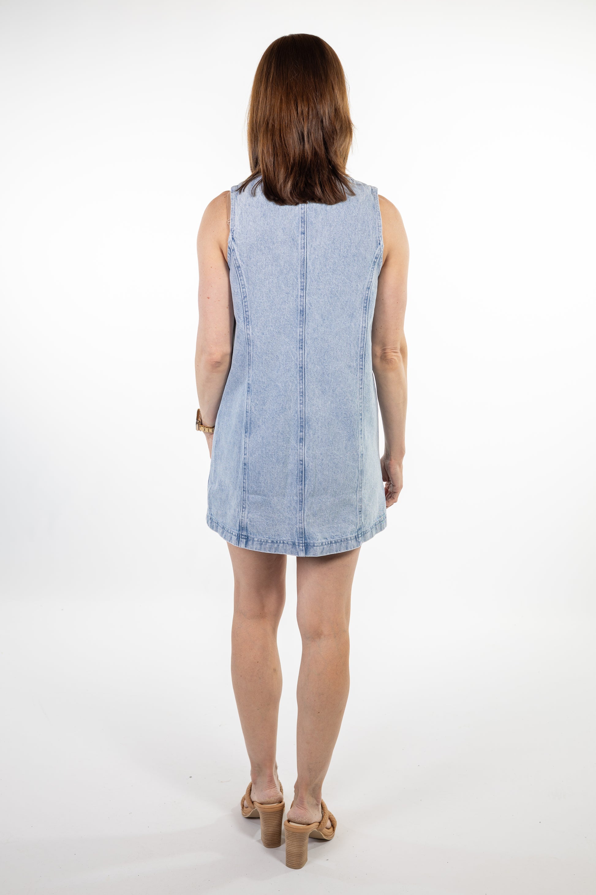 Woman wearing a light blue denim dress on a white background