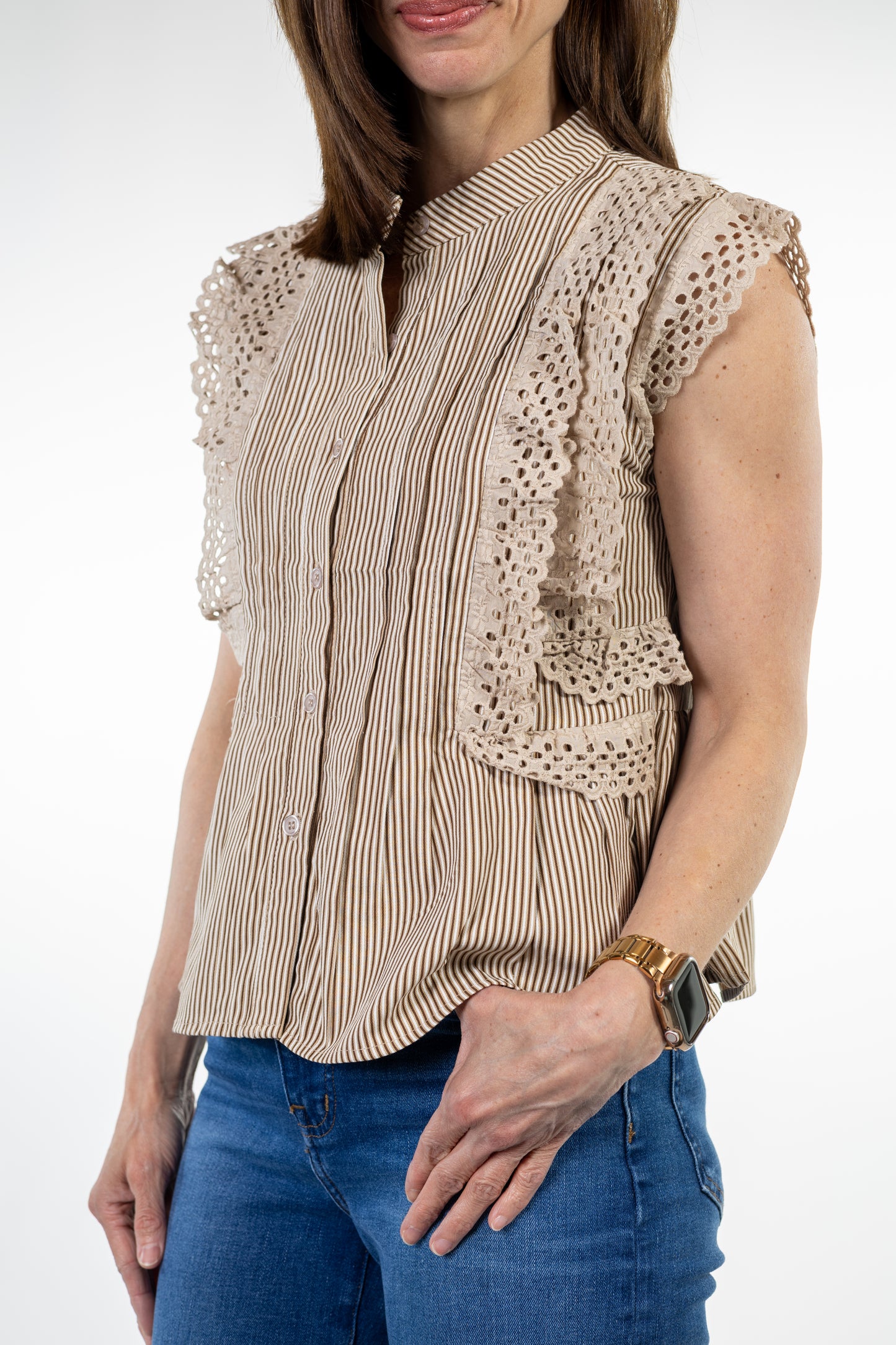Woman wearing a beige blouse with lace details and blue jeans on a white background