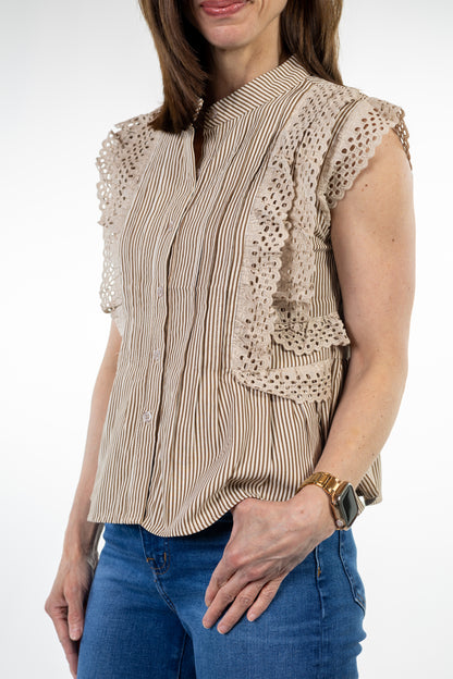 Woman wearing a beige blouse with lace details and blue jeans on a white background