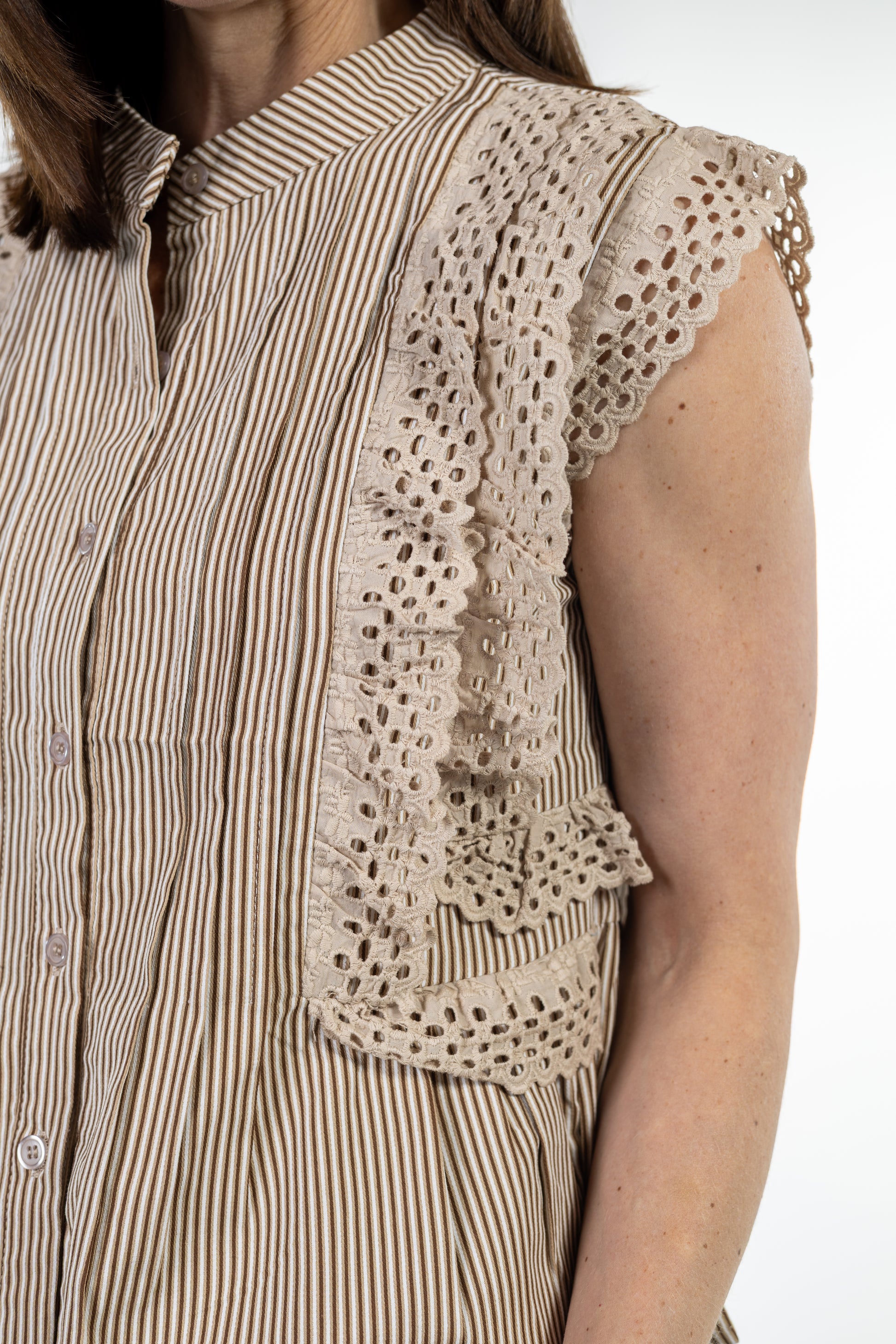Woman wearing a beige striped shirt with a lace detail on a white background