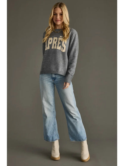 Woman wearing a gray sweater with 'APRES' text and blue jeans on a gray background