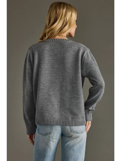 Person wearing a gray sweater and blue jeans against a plain background