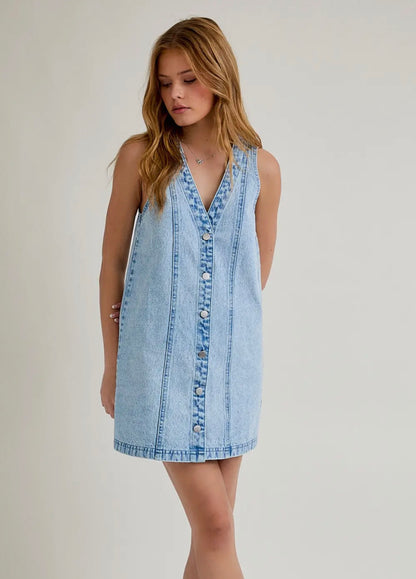 Woman wearing a light blue denim dress against a plain background