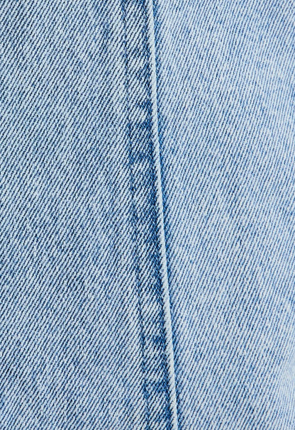 Close-up of blue denim fabric with a visible seam.