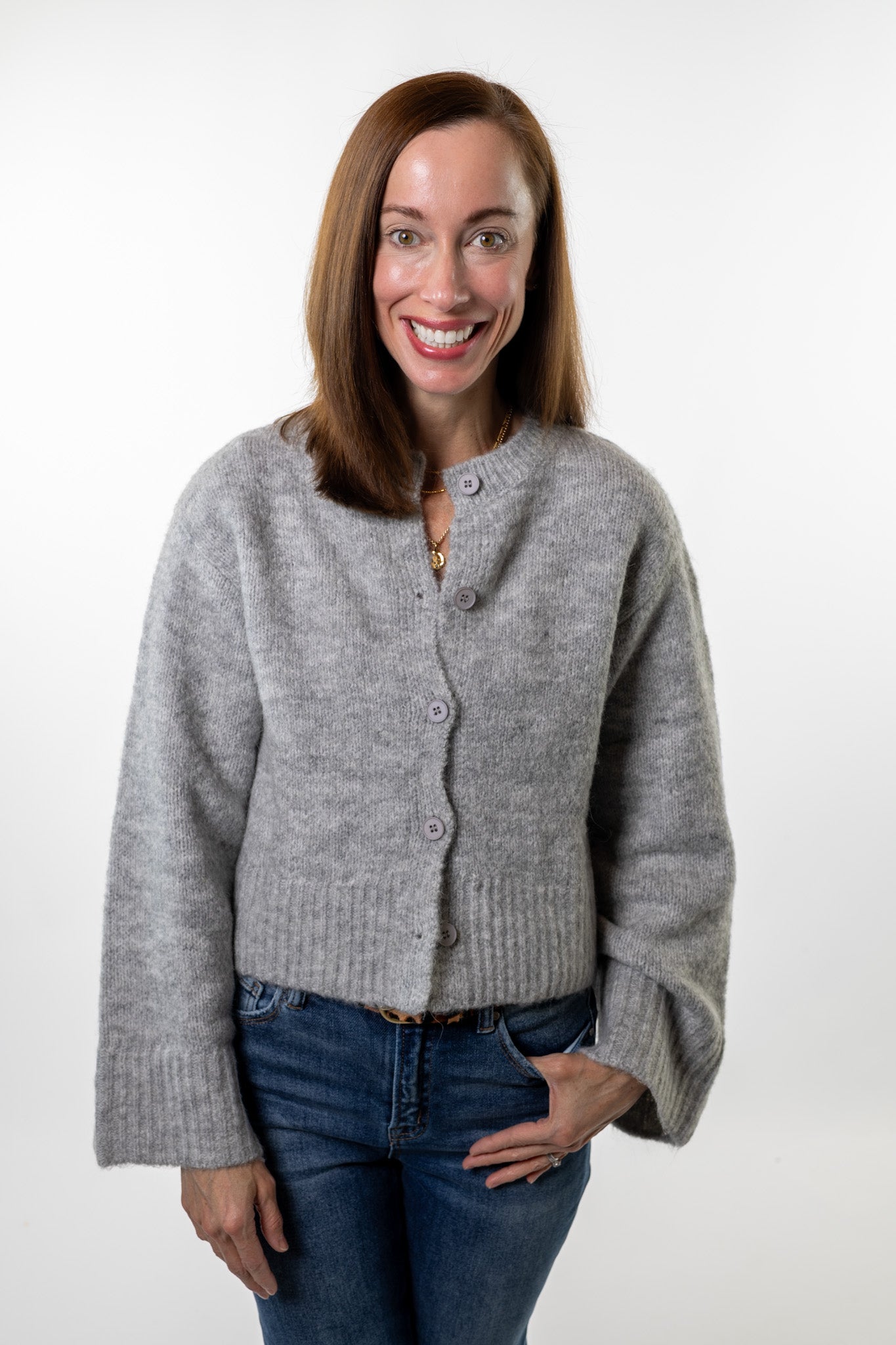 Woman wearing a soft gray button-front cardigan sweater with relaxed sleeves and classic blue jeans — cozy fall outfit from Salt & Lavender Clothing, a boutique in Dublin and Powell, Ohio.