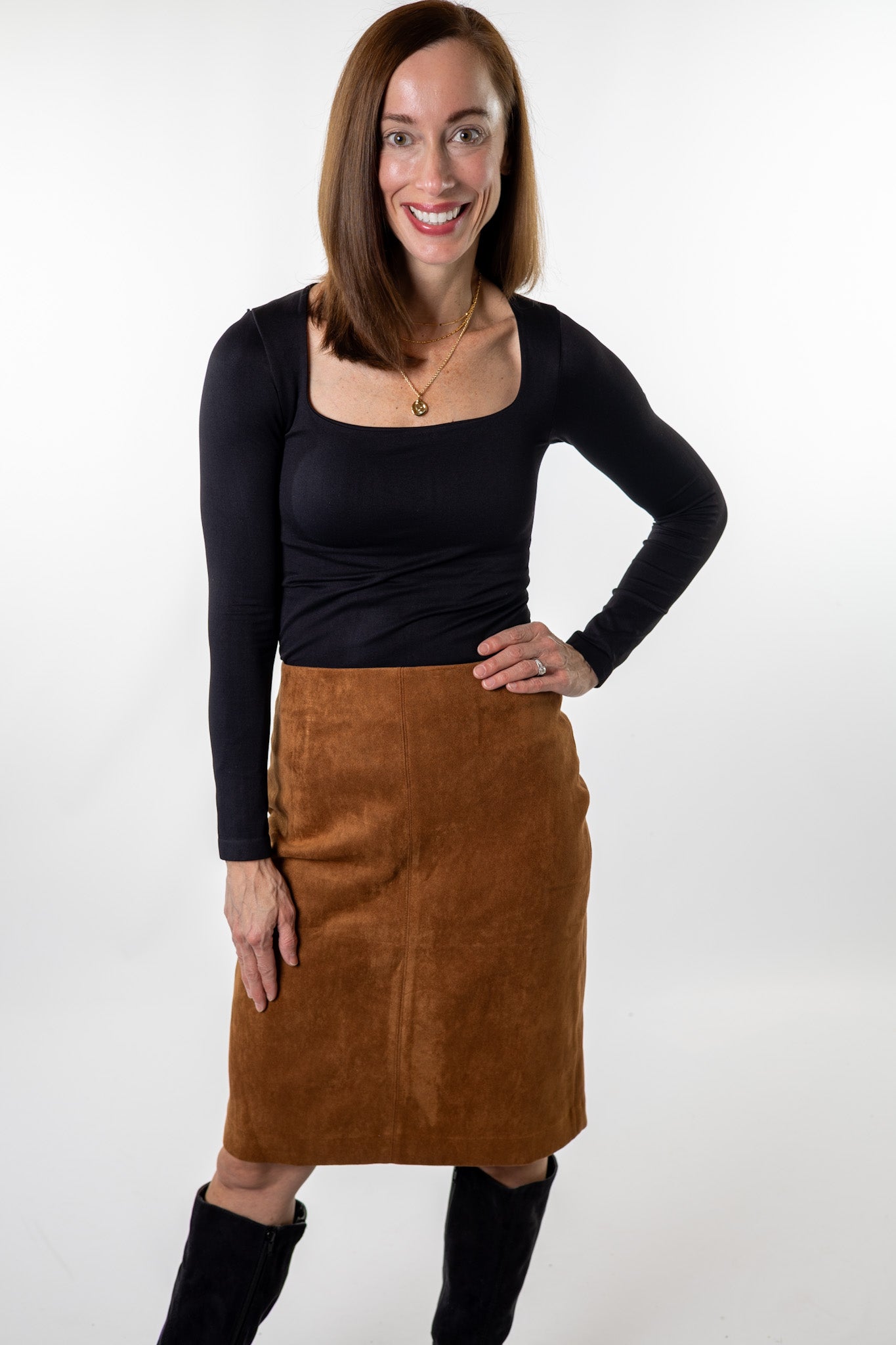 Woman wearing a camel suede pencil skirt from Salt & Lavender Clothing, styled with a fitted black long-sleeve top and knee-high boots — chic fall outfit for work or dinner in Dublin and Powell, Ohio.