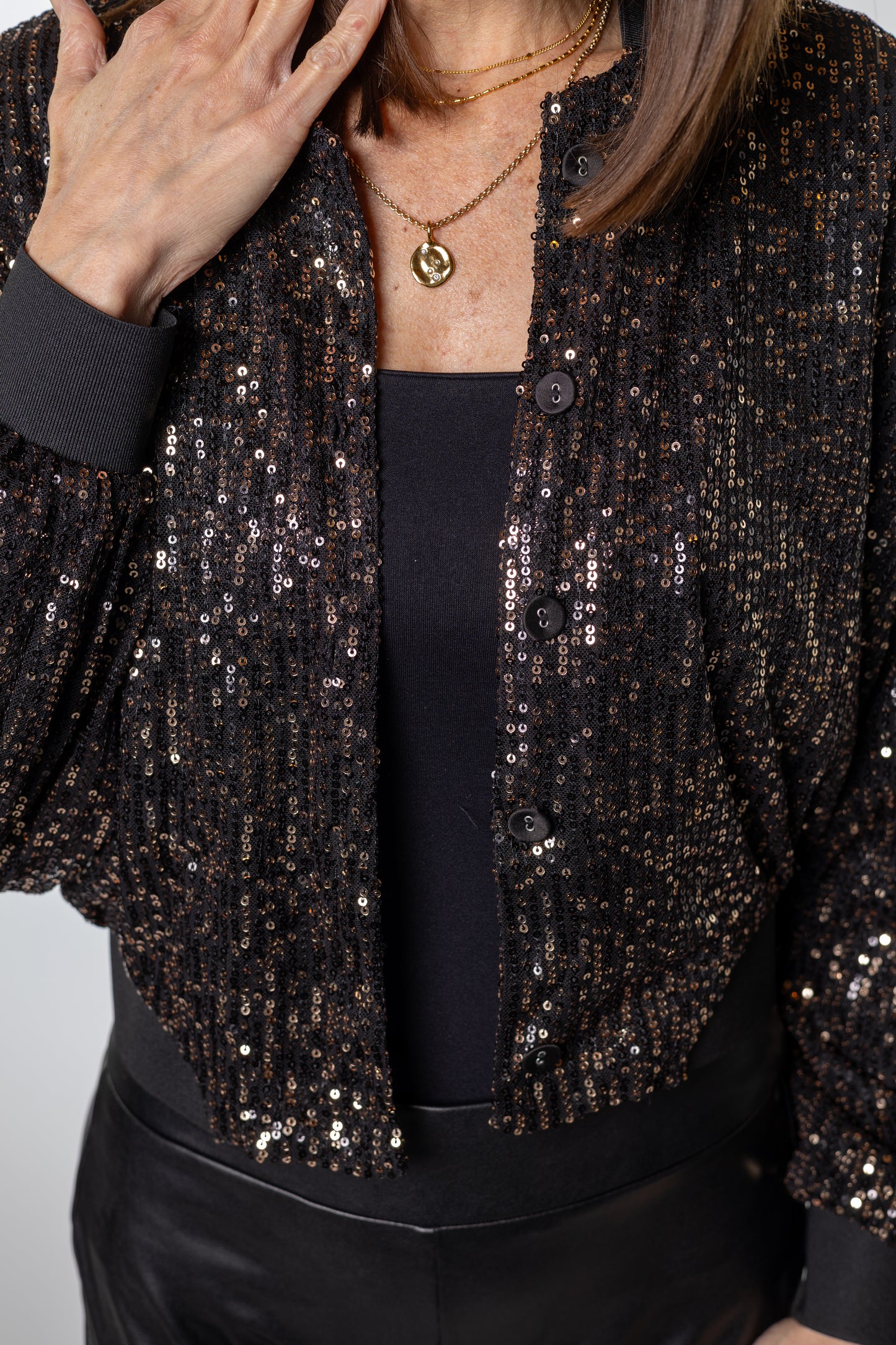 Close-up of shimmering black bomber jacket with gold sequins — effortless sparkle that dresses up any look from Salt & Lavender Clothing.