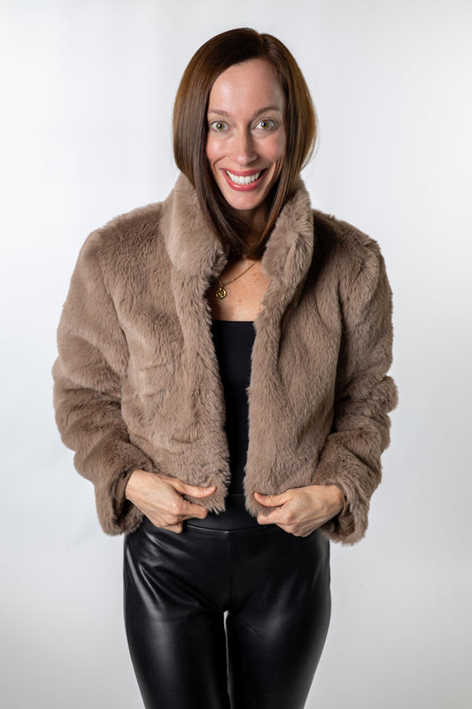 Woman wearing a taupe faux-fur cropped jacket with black leather pants — cozy and chic winter outfit from Salt & Lavender Clothing, perfect for holiday dinners or nights out.