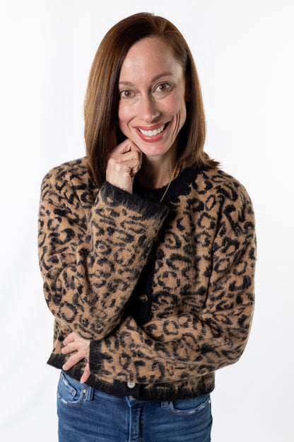 Woman wearing a leopard print sweater and blue jeans on a white background