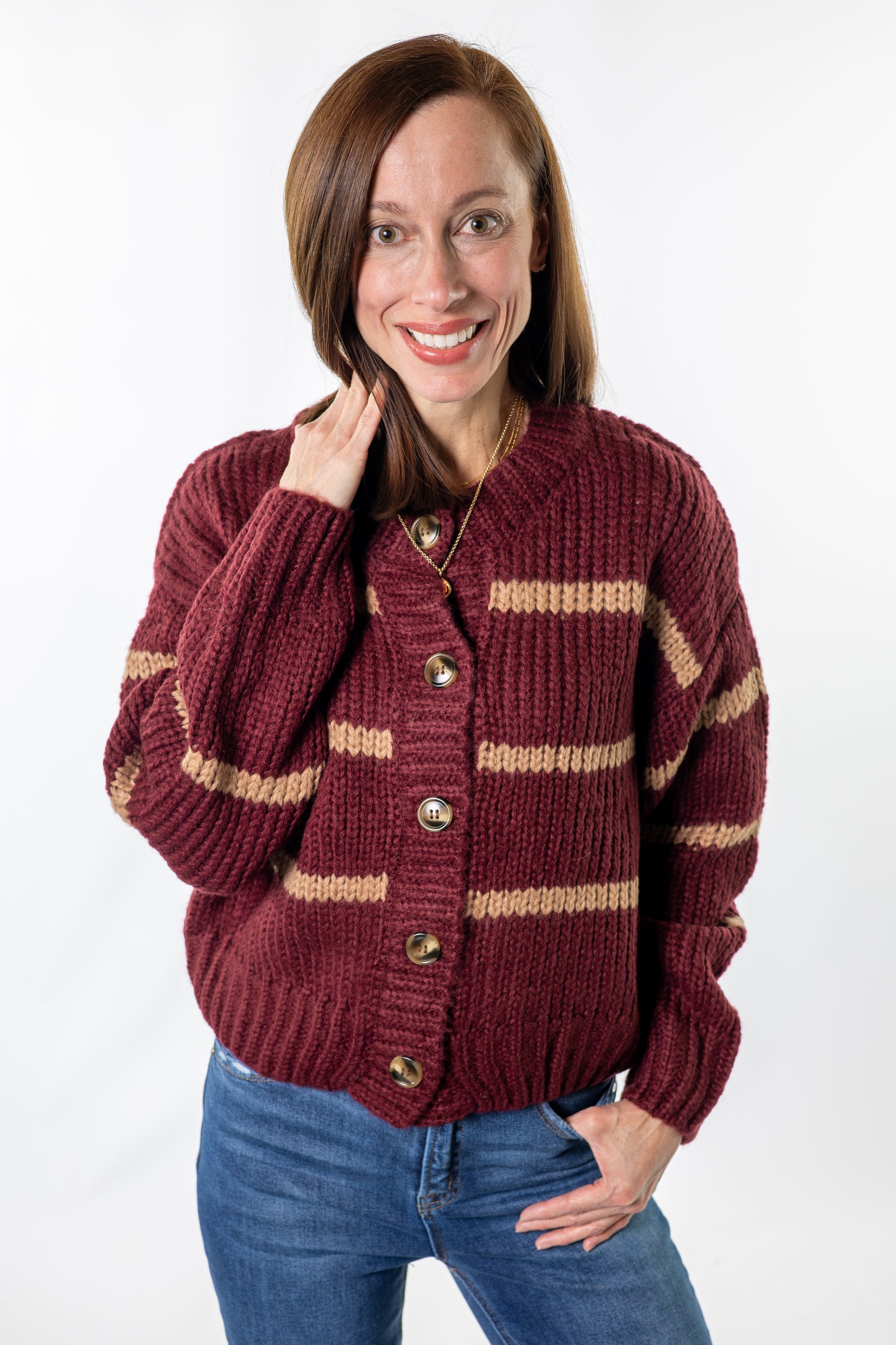Woman wearing a maroon cardigan with gold stripes on a white background