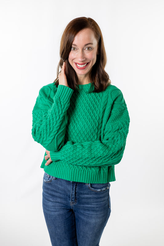 Woman wearing a green sweater and blue jeans on a white background