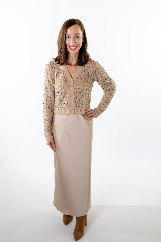 Woman wearing a beige sequin top and champagne skirt on a white background