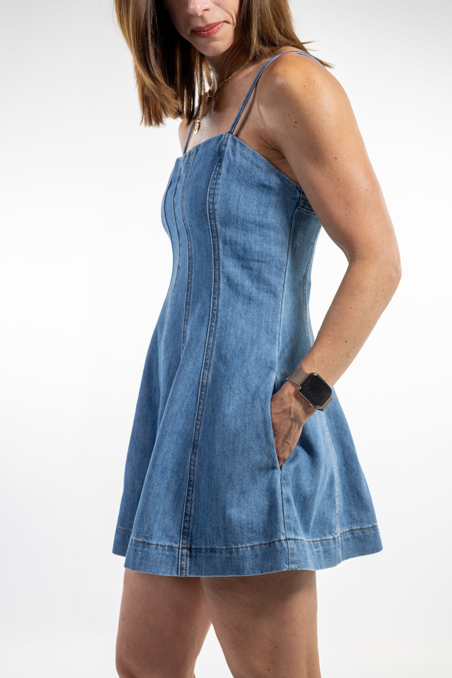 Woman wearing a blue denim romper dress on a white background