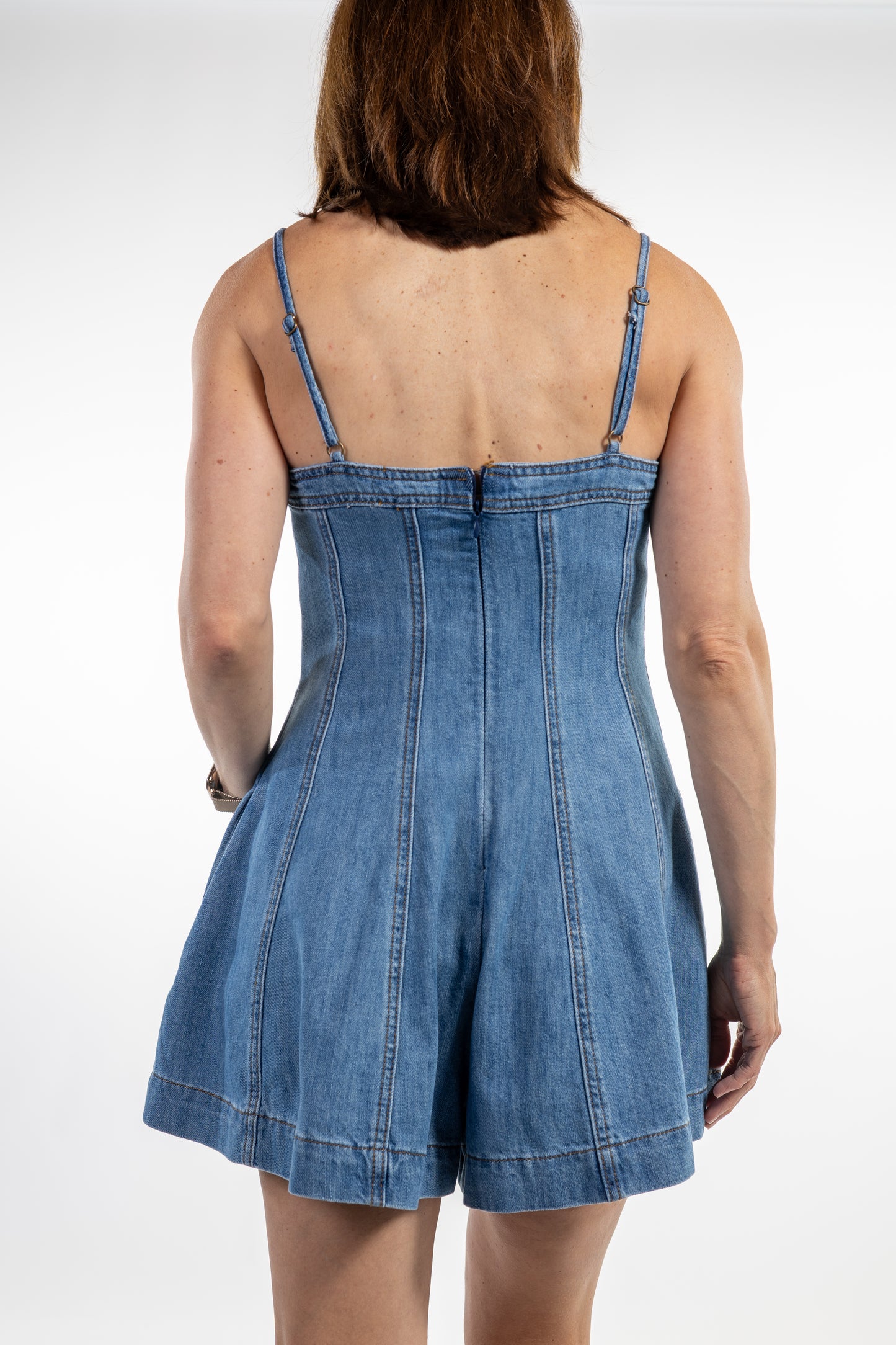 Person wearing a blue denim romper on a white background