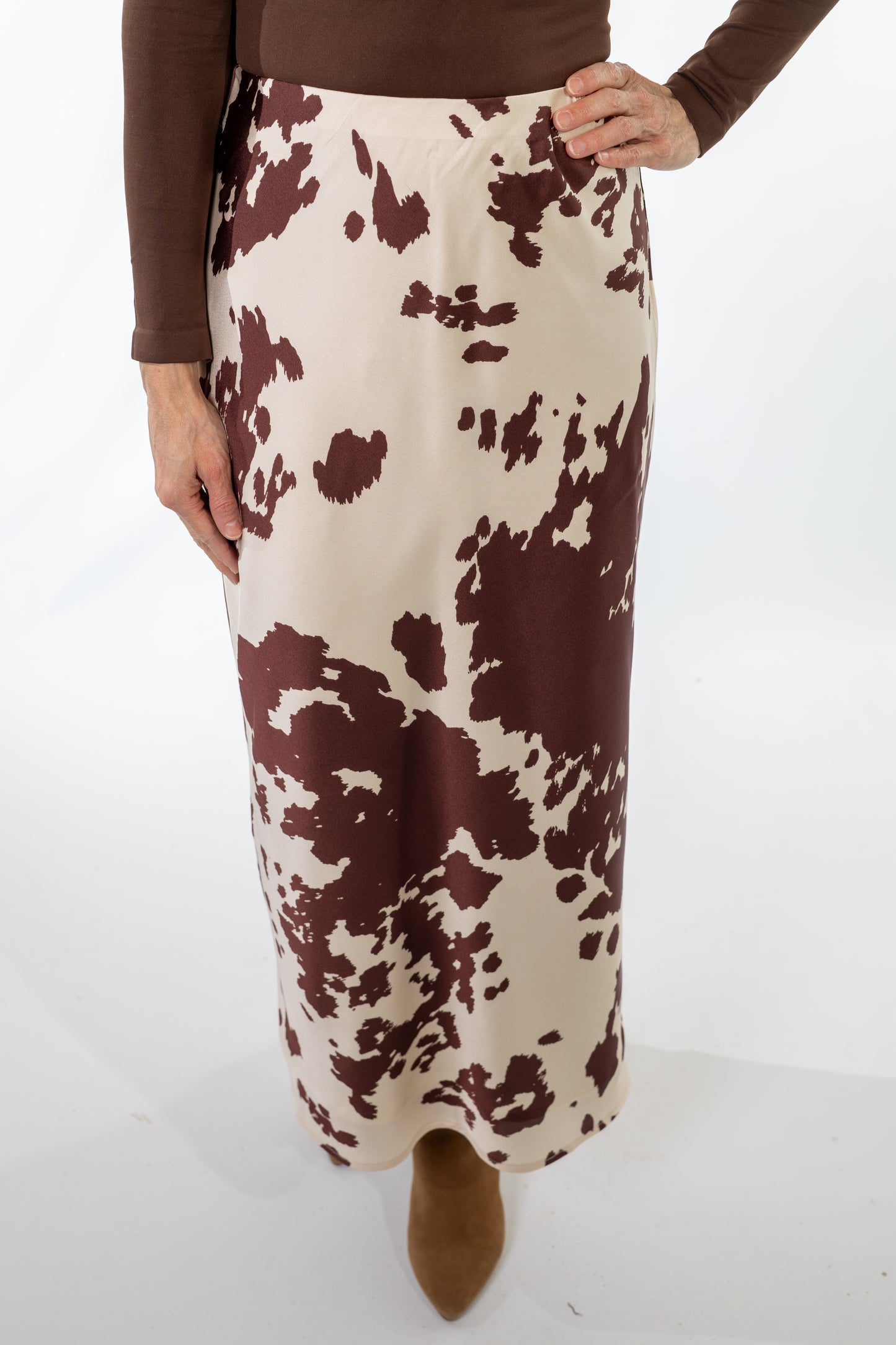 Person wearing a brown and white animal patterned skirt on a white background
