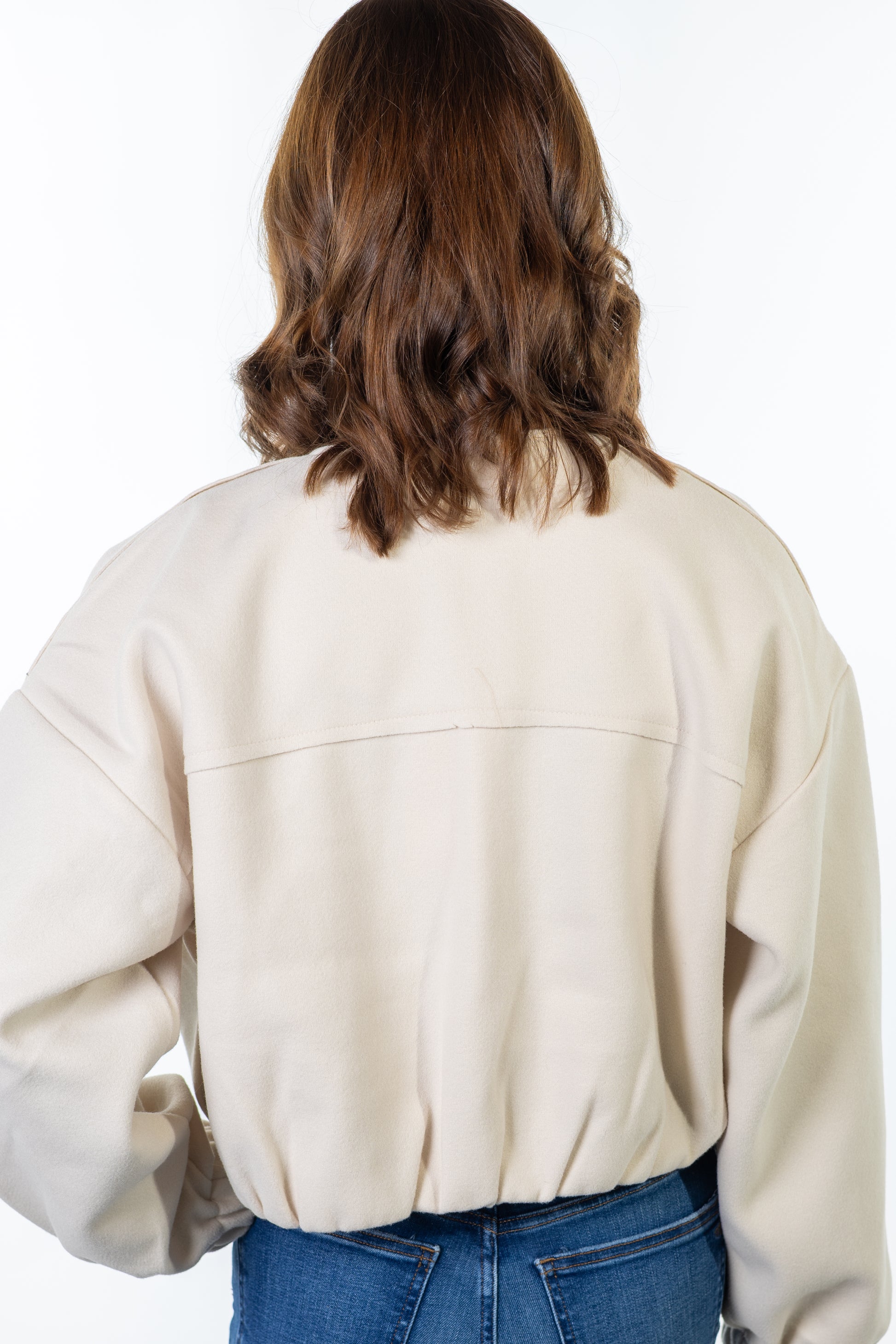 Person wearing a cream-colored jacket on a white background