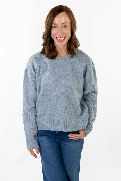 Woman wearing a gray sweater and blue jeans on a white background