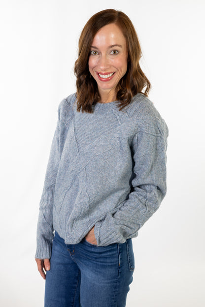 Woman wearing a gray sweater and blue jeans on a white background
