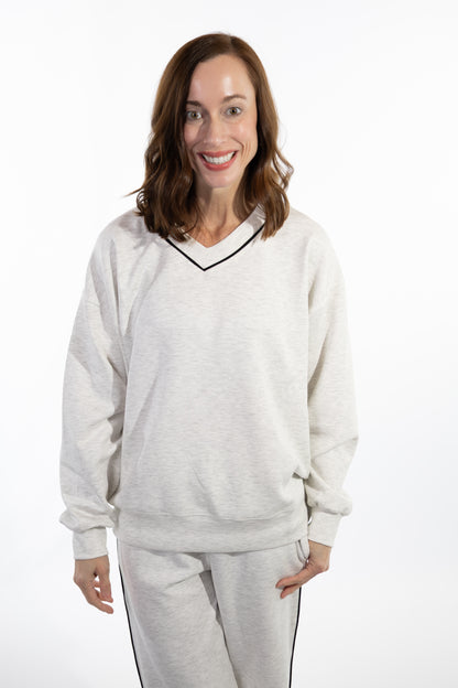 Woman wearing a light gray scuba sweatshirt and pants on a white background