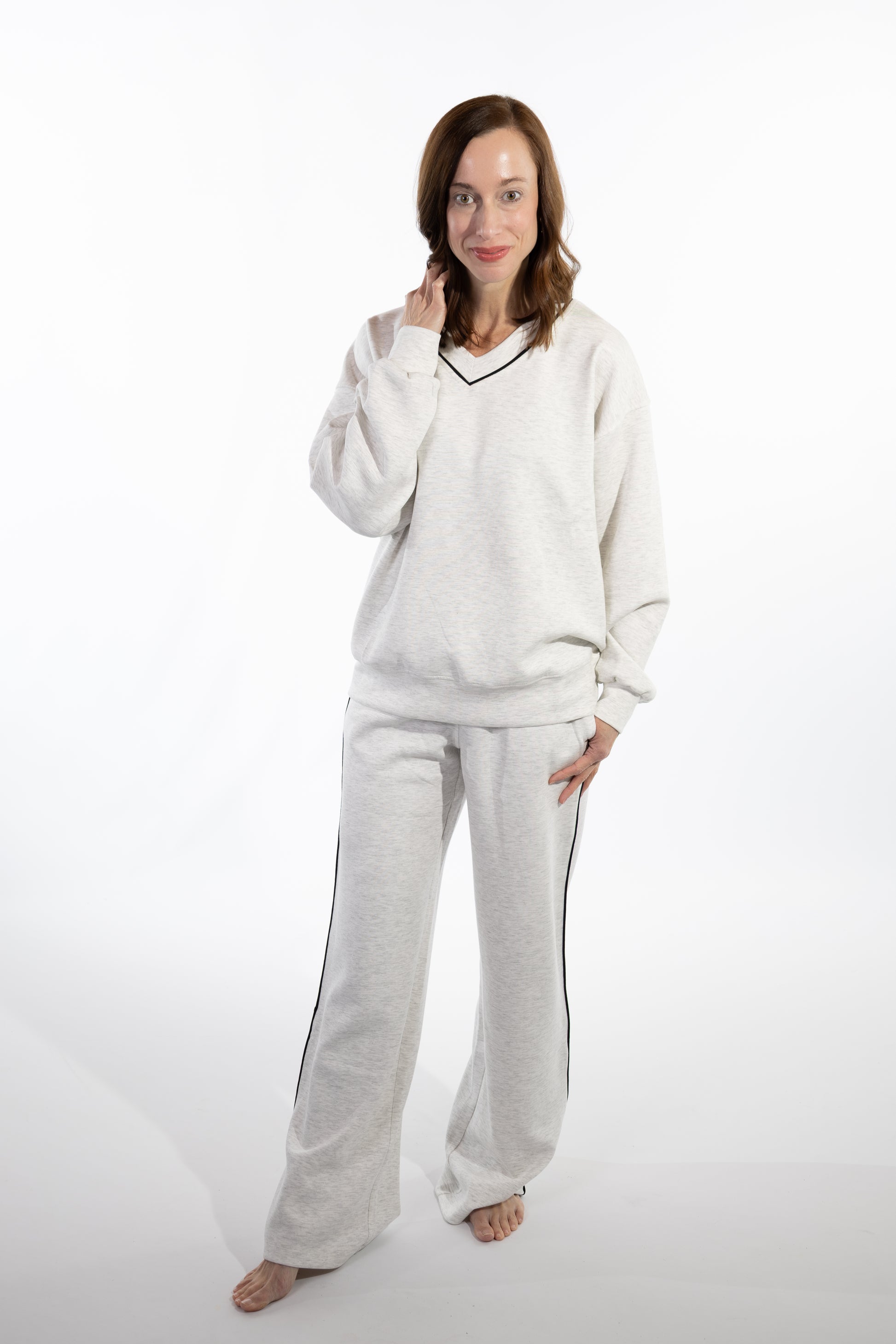 Woman wearing a light gray scuba pajama set on a white background