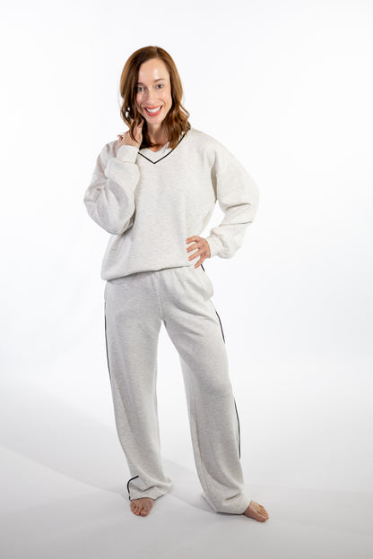 Woman wearing a light gray with black piping scuba loungewear set on a white background