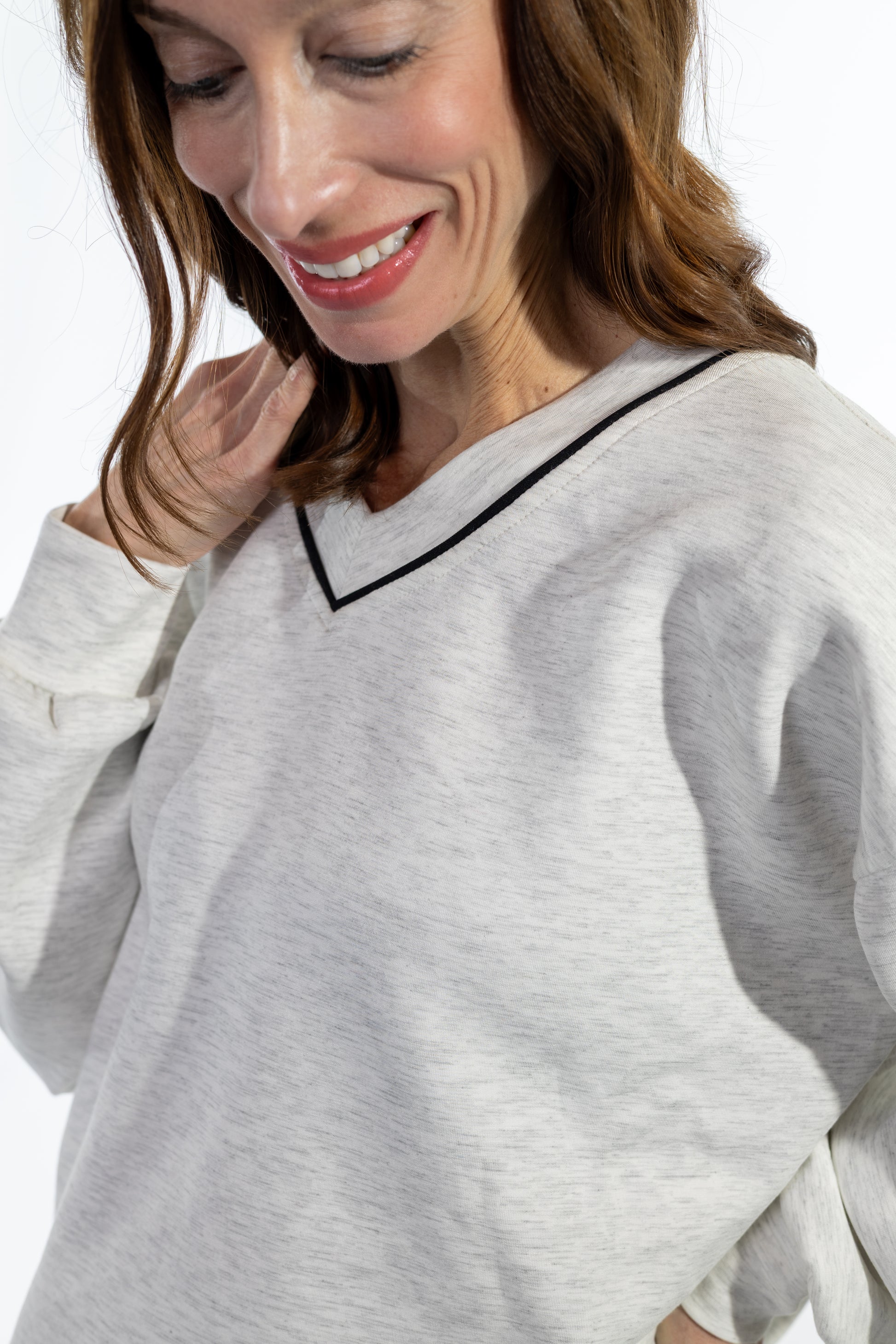 Woman wearing a gray scuba top sweater with a white background