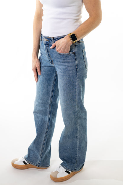 Person wearing blue jeans and a white top on a white background