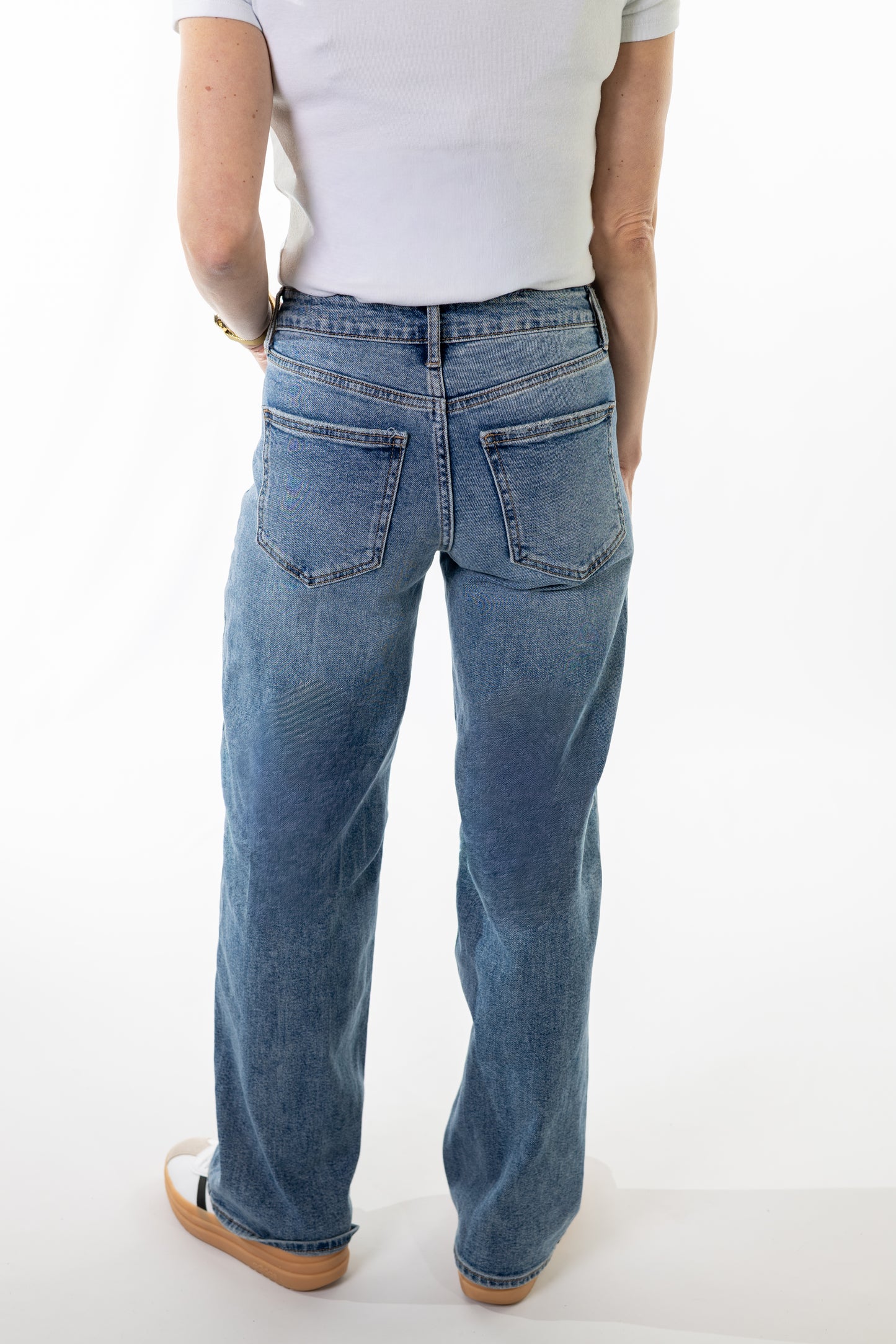 Person wearing blue jeans and a white shirt on a white background