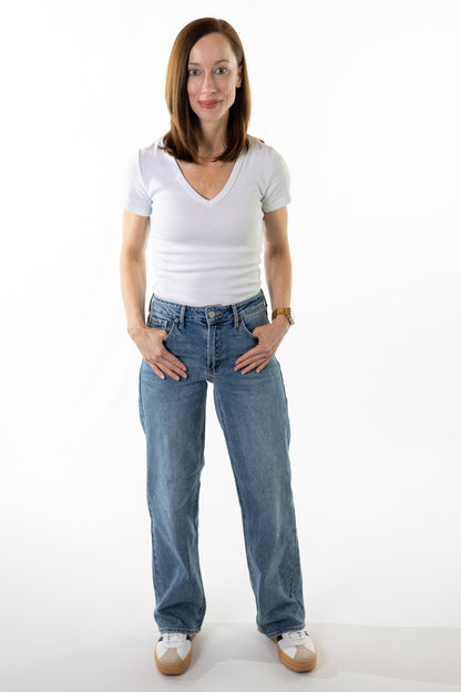 Woman wearing a white t-shirt and blue jeans on a white background