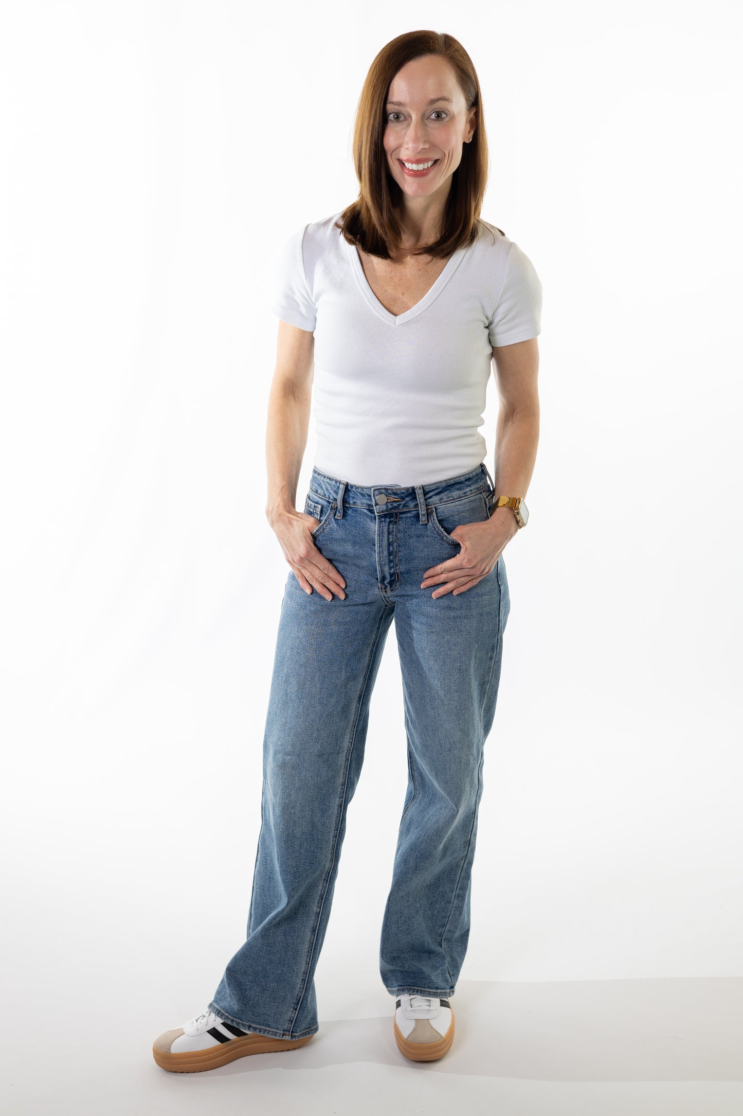 Woman wearing a white t-shirt and blue jeans on a white background