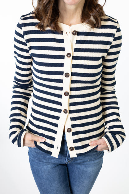 Person wearing a navy and white striped cardigan with blue jeans on a white background