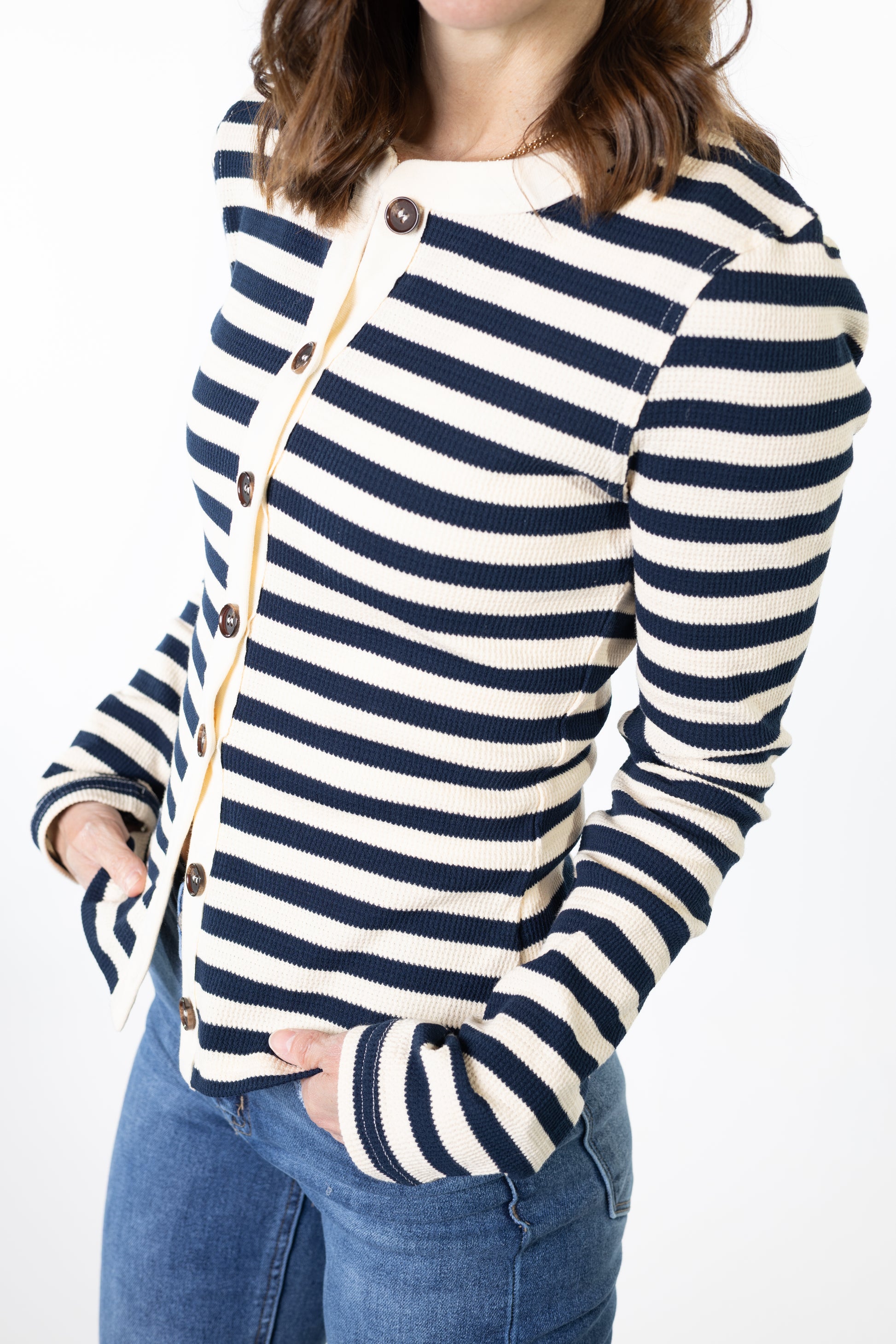 Person wearing a navy and white striped sweater with buttons on a plain background