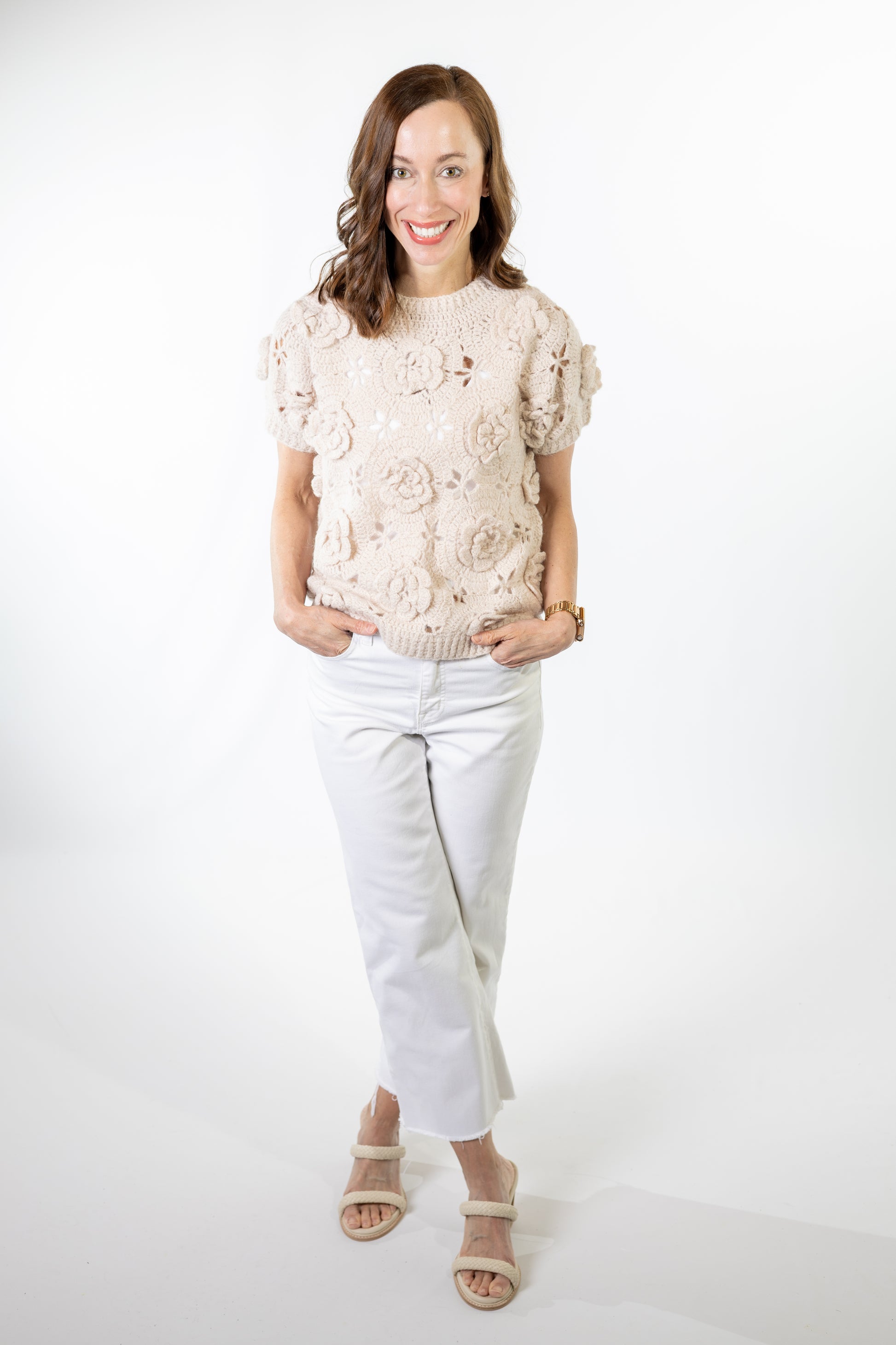 Woman wearing a floral top and white pants on a white background