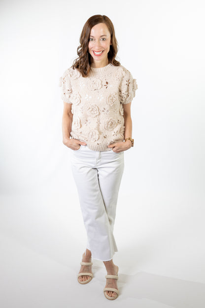 Woman wearing a floral top and white pants on a white background