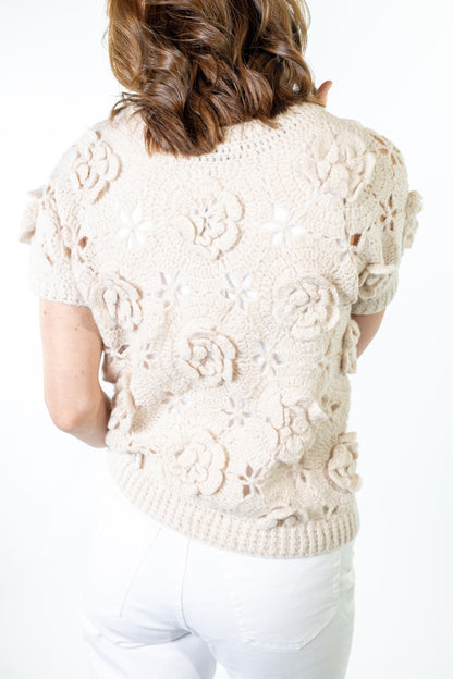 Woman wearing a cream-colored florak knit cardigan on a white background