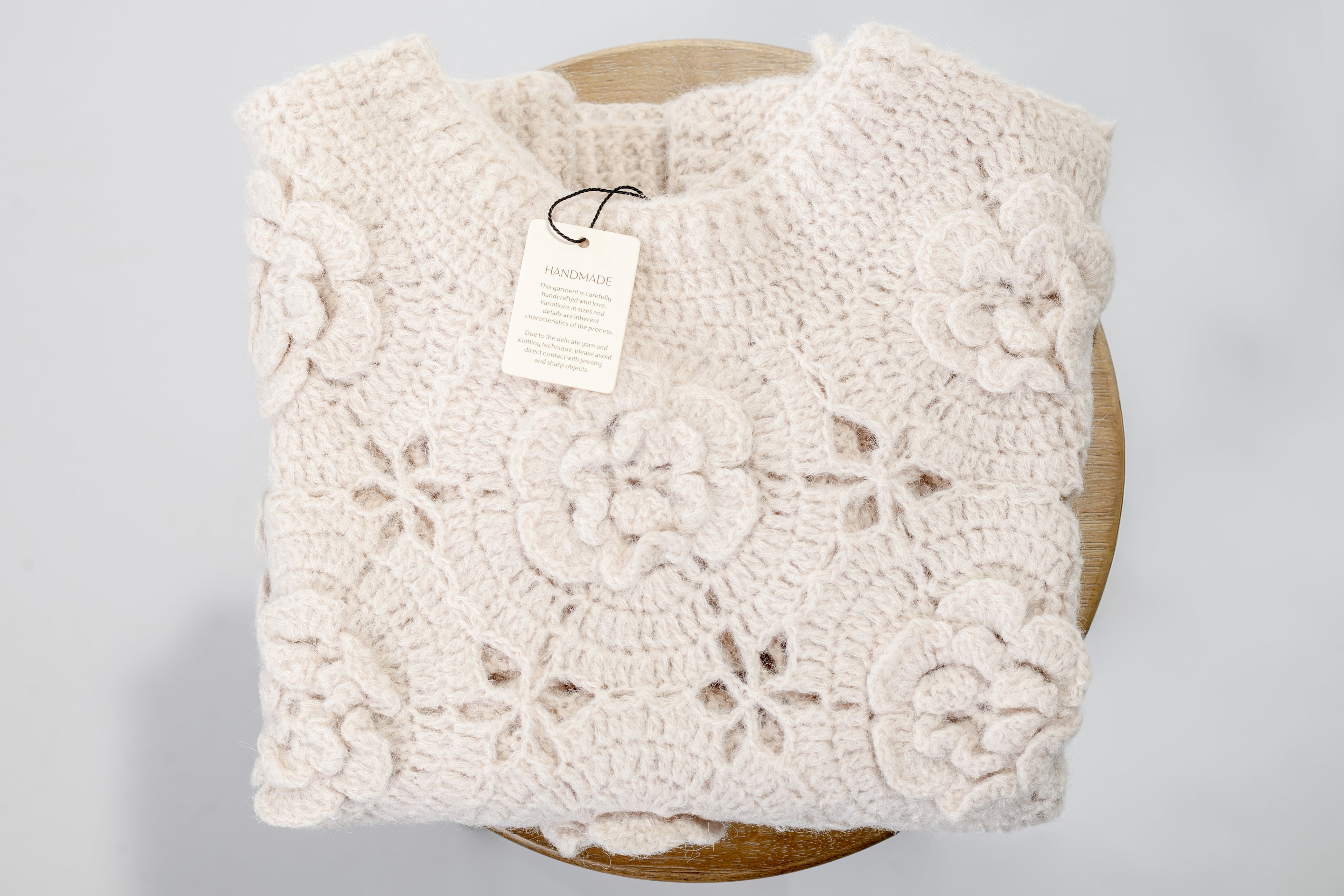 Beige crochet blanket on a wooden surface with a gray background