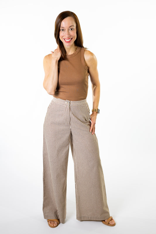 Woman wearing a brown sleeveless top and brown stiped high rise wide-leg pants on a white background
