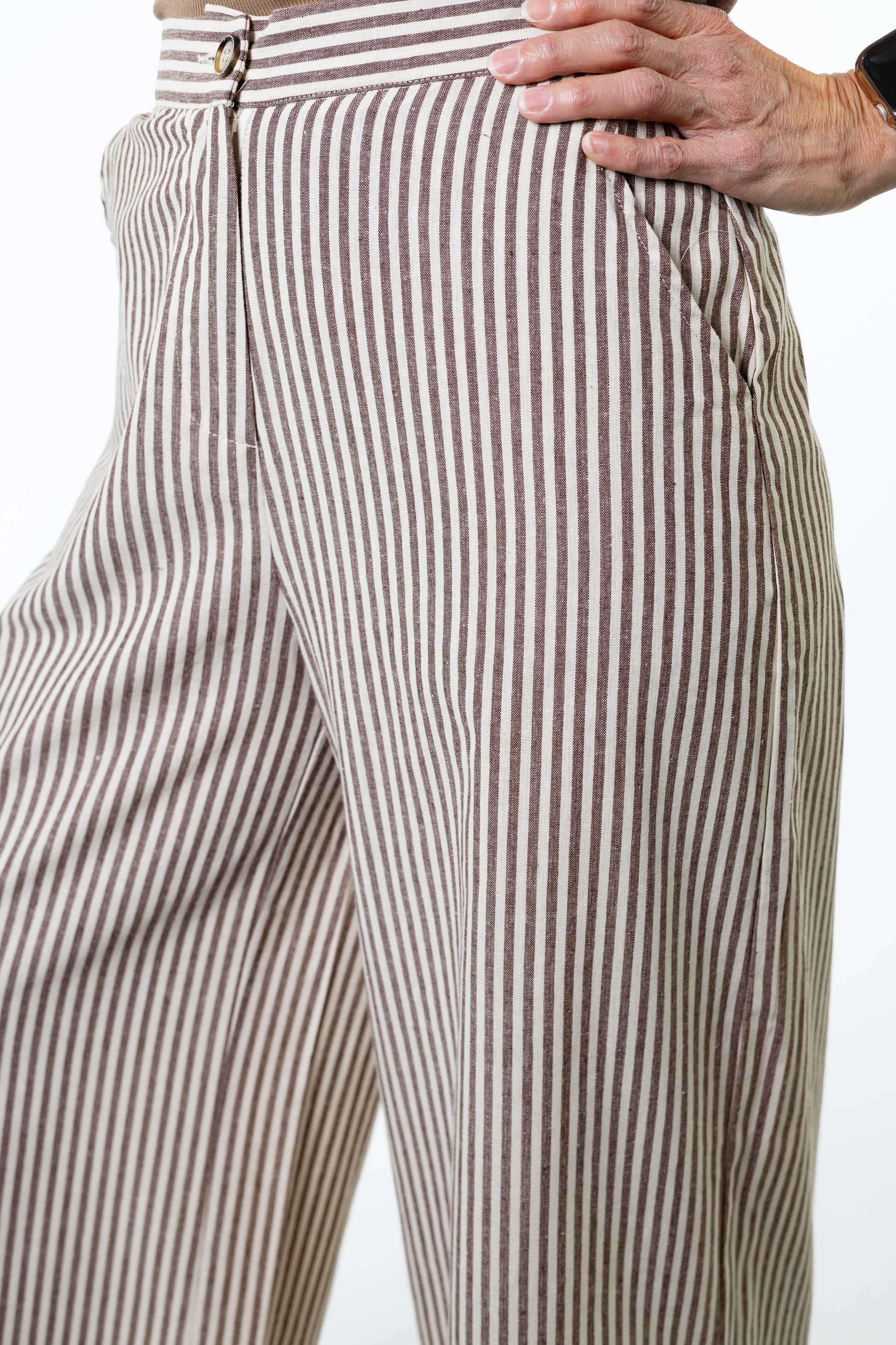 Close-up of a person wearing brown and white striped pants on a white background