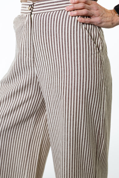 Close-up of a person wearing brown and white striped pants on a white background