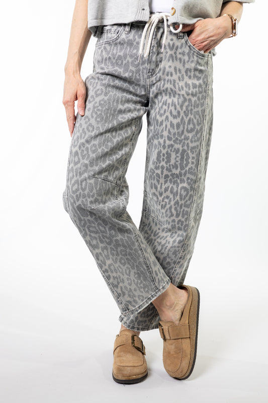 Person wearing gray leopard print pants with brown shoes on a white background